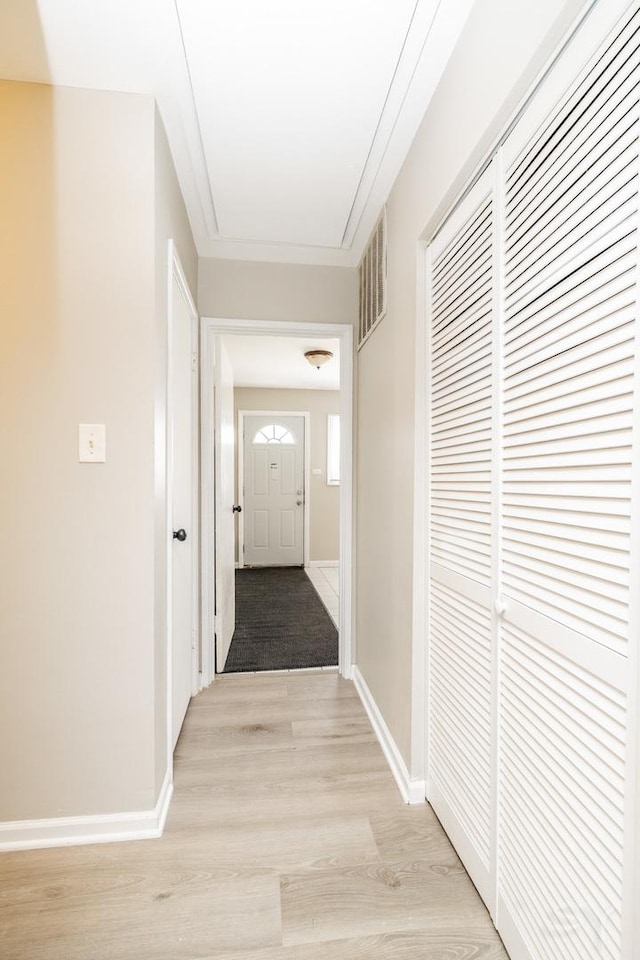 corridor featuring light wood finished floors, visible vents, and baseboards