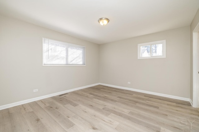 unfurnished room featuring light wood finished floors, visible vents, and baseboards