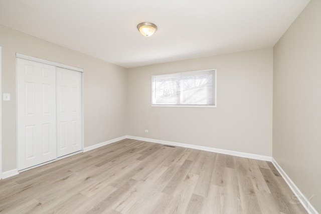 unfurnished bedroom with a closet, baseboards, and light wood-style flooring