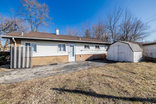 rear view of property with an outbuilding, a chimney, a storage unit, and a patio