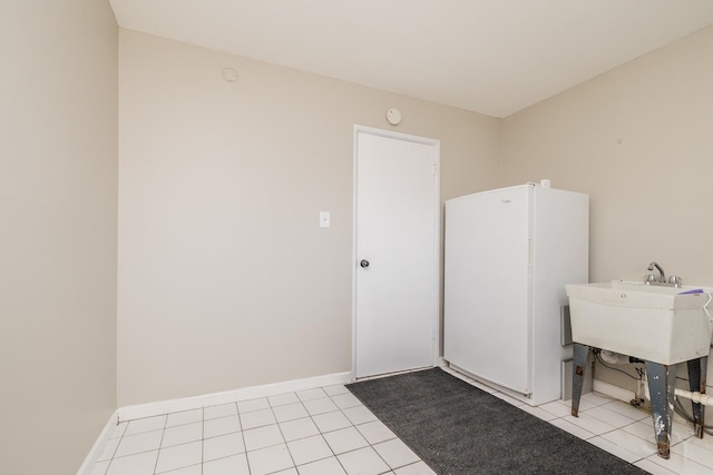 clothes washing area with light tile patterned floors and baseboards