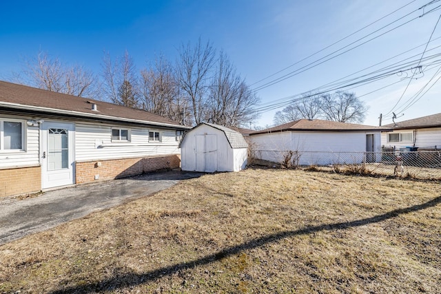 rear view of house featuring a storage shed, fence, brick siding, and an outbuilding