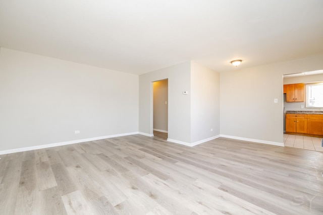 spare room with baseboards and light wood-style flooring