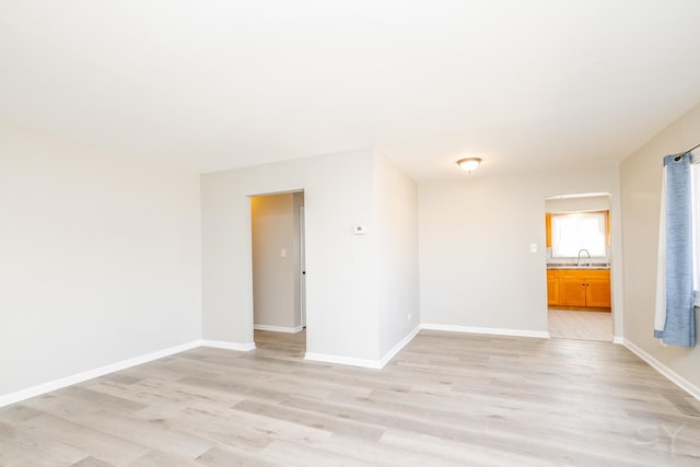 unfurnished room featuring a sink, baseboards, and light wood finished floors