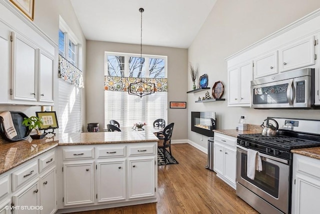 kitchen with white cabinets, appliances with stainless steel finishes, a peninsula, and wood finished floors