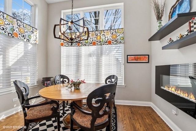 dining area featuring baseboards, an inviting chandelier, and wood finished floors