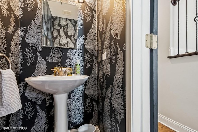 half bathroom with wood finished floors and baseboards