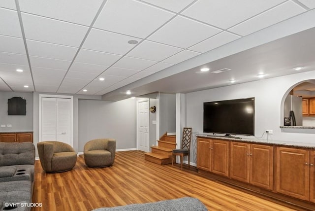 living room with baseboards, recessed lighting, stairs, light wood-style floors, and a paneled ceiling