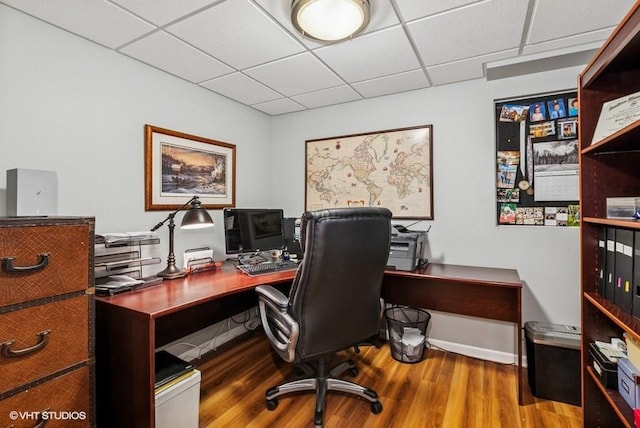 office space with a drop ceiling, baseboards, and wood finished floors