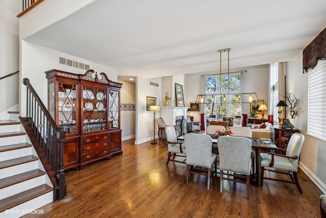 dining area with stairs, wood finished floors, visible vents, and baseboards