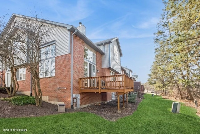 view of home's exterior featuring a deck, a yard, brick siding, and a chimney