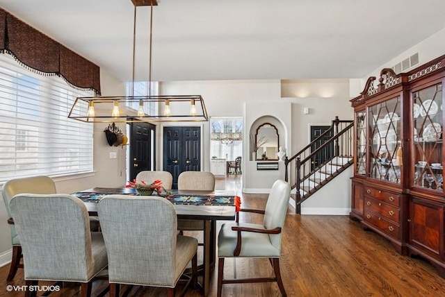 dining area with stairway, baseboards, visible vents, and wood finished floors