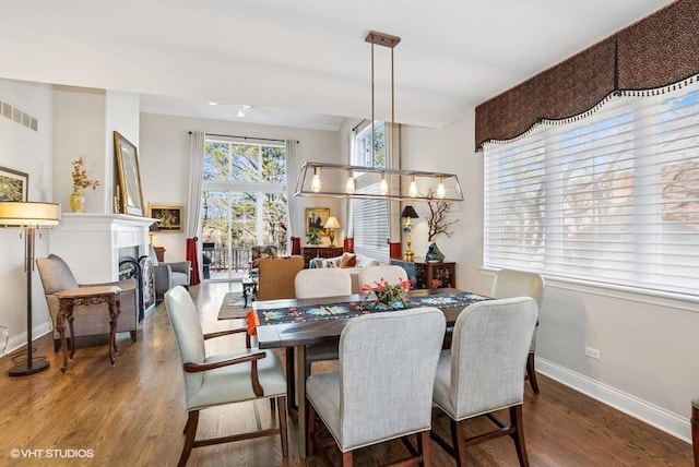 dining area featuring visible vents, baseboards, wood finished floors, and a fireplace