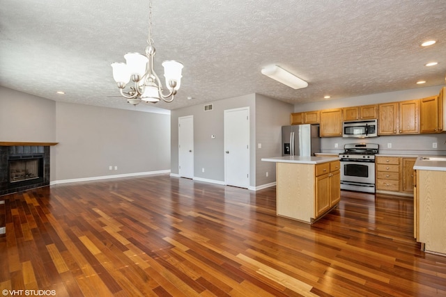 kitchen featuring a notable chandelier, a kitchen island, open floor plan, stainless steel appliances, and light countertops