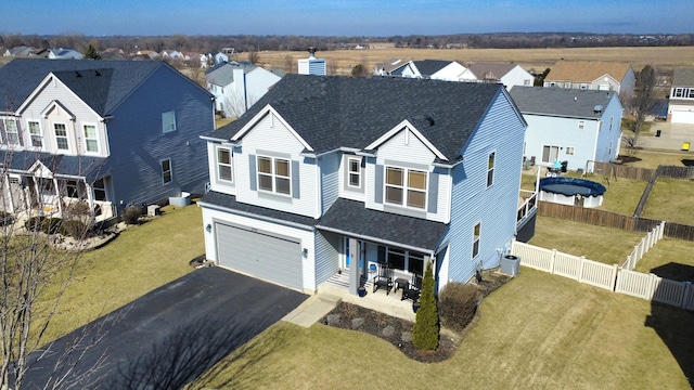 traditional home with a garage, a residential view, fence, and aphalt driveway