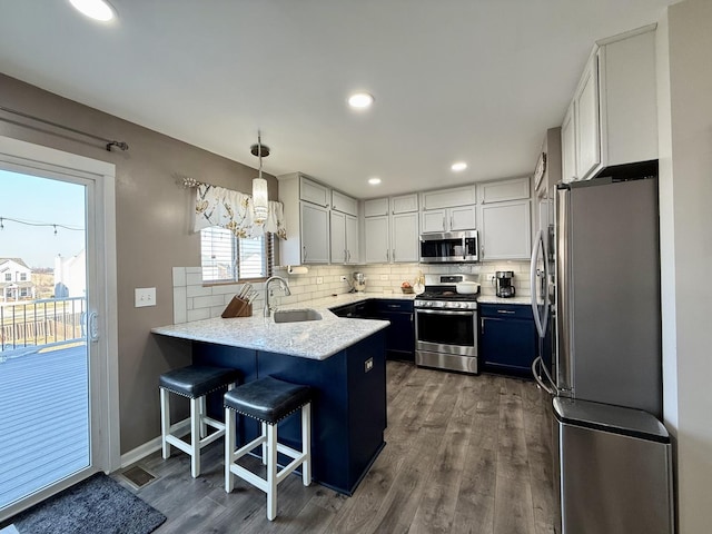 kitchen with a peninsula, tasteful backsplash, appliances with stainless steel finishes, and a sink