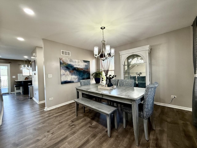 dining space featuring dark wood finished floors, visible vents, baseboards, and an inviting chandelier