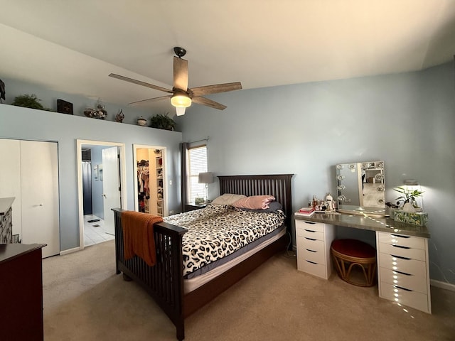 bedroom with ceiling fan, a walk in closet, light carpet, and connected bathroom