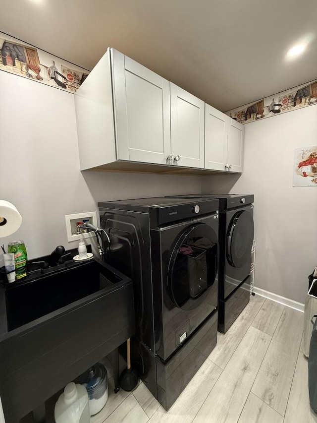 laundry area with baseboards, washer and clothes dryer, light wood-style floors, cabinet space, and a sink