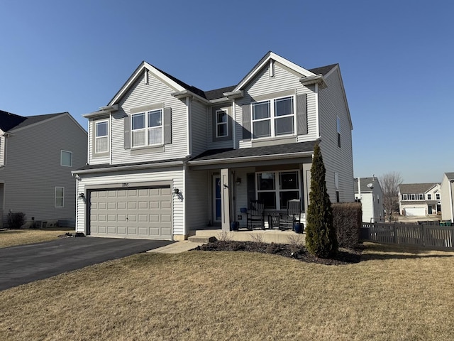 traditional home with fence, driveway, an attached garage, covered porch, and a front lawn