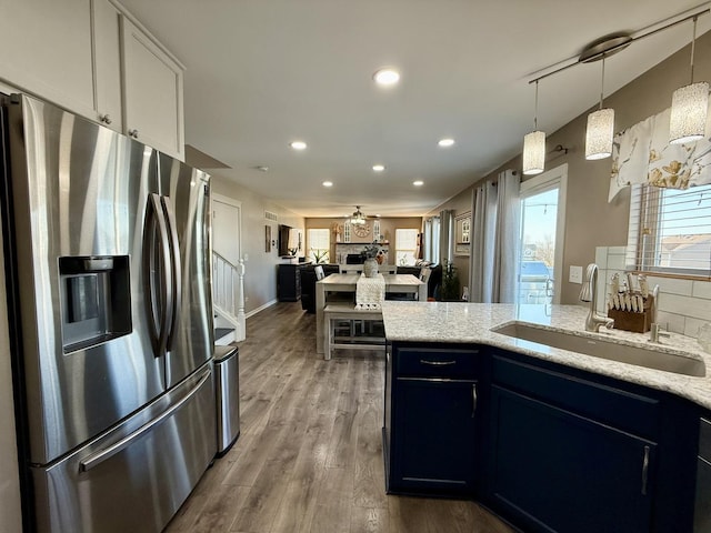 kitchen featuring light stone counters, wood finished floors, recessed lighting, a sink, and stainless steel refrigerator with ice dispenser