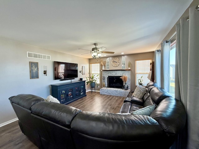 living area featuring visible vents, a fireplace, dark wood-type flooring, and baseboards