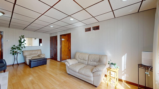 living area featuring light wood-type flooring and a paneled ceiling