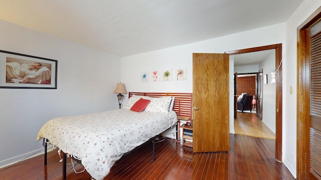 bedroom with dark wood finished floors and baseboards