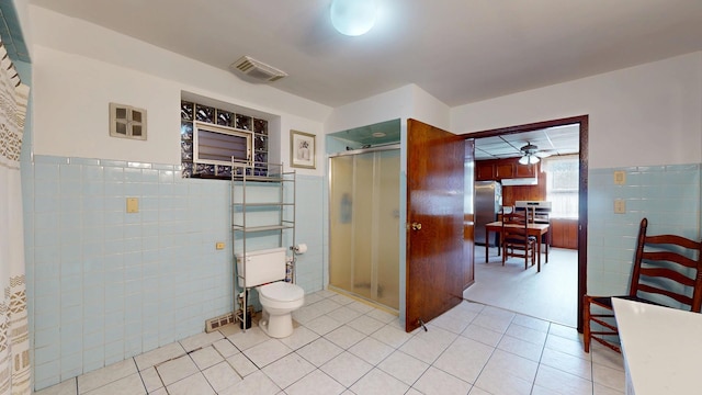 full bathroom featuring visible vents, a shower stall, wainscoting, tile walls, and toilet