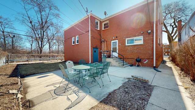 back of house featuring brick siding, a patio, and fence