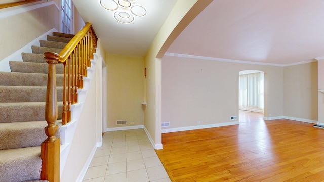 interior space with visible vents, arched walkways, light wood-style floors, crown molding, and baseboards