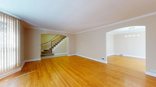 unfurnished room featuring arched walkways, visible vents, light wood finished floors, and stairs