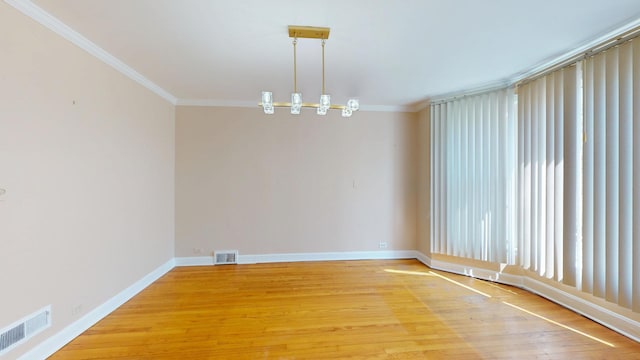 empty room with crown molding, visible vents, and light wood-type flooring