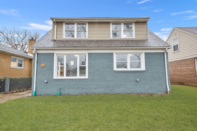 view of front of home featuring fence, brick siding, a front lawn, and a shingled roof