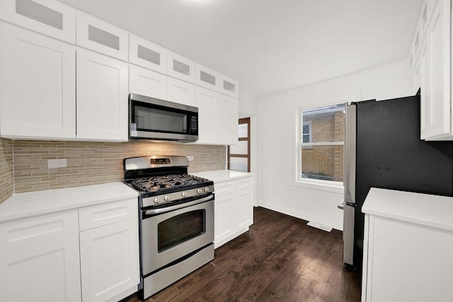 kitchen with tasteful backsplash, appliances with stainless steel finishes, dark wood finished floors, and white cabinetry