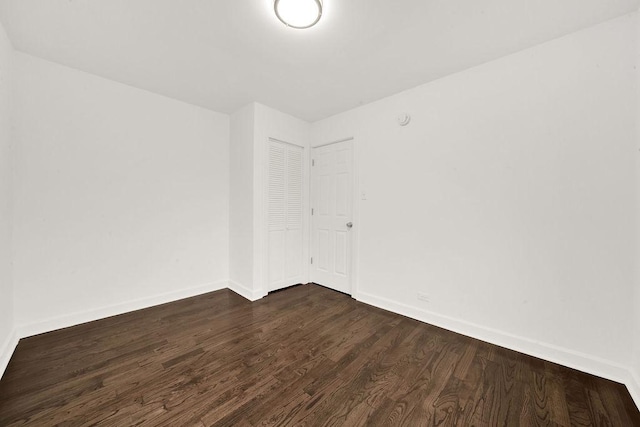 spare room featuring dark wood finished floors and baseboards