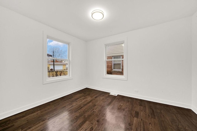 spare room featuring baseboards and dark wood-style flooring