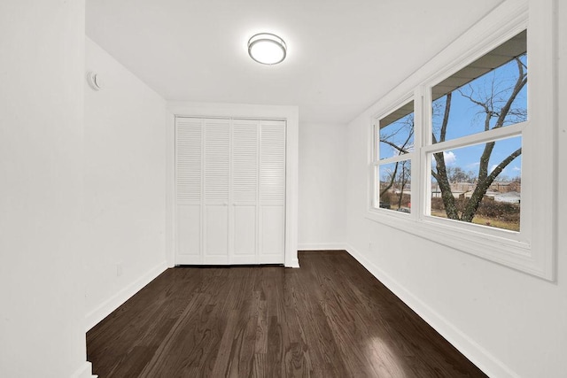 unfurnished bedroom with a closet, baseboards, and dark wood finished floors