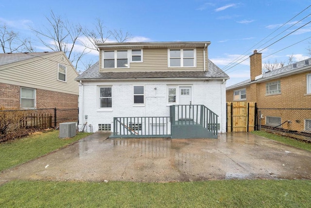 back of house featuring brick siding, cooling unit, roof with shingles, and fence