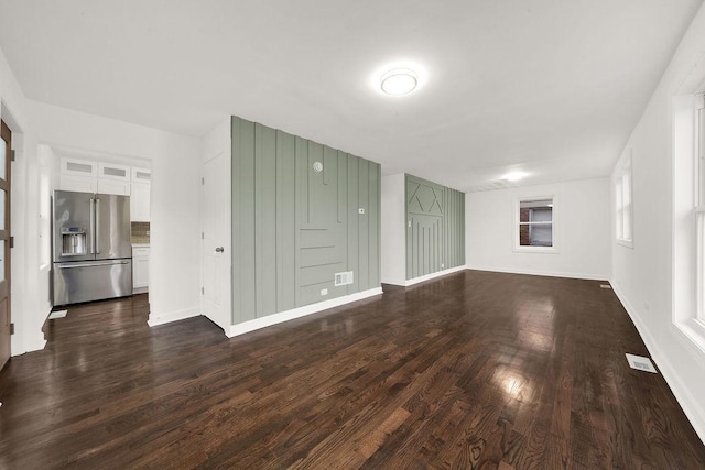 unfurnished living room with visible vents, baseboards, and dark wood-style flooring