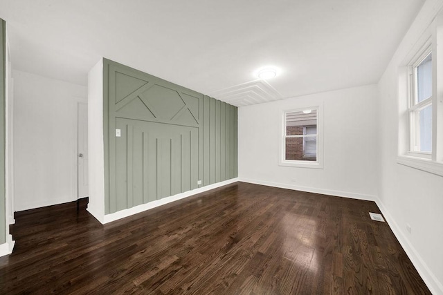 spare room with visible vents, dark wood-type flooring, and baseboards