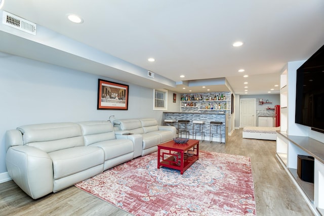 living area with recessed lighting, visible vents, indoor bar, and light wood-style flooring