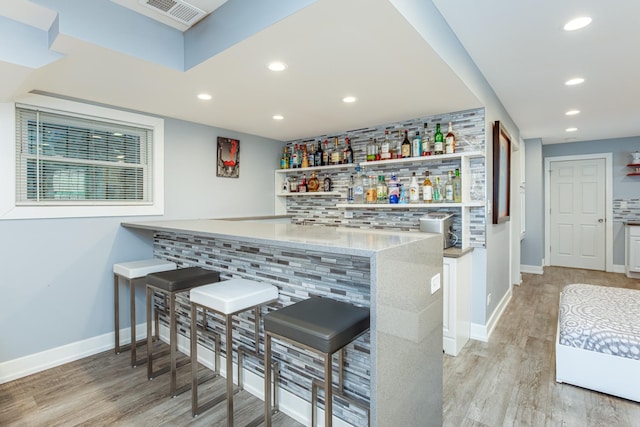 bar with baseboards, visible vents, recessed lighting, light wood-type flooring, and indoor bar