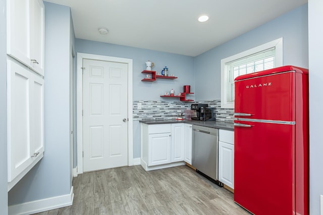 kitchen featuring stainless steel dishwasher, dark countertops, freestanding refrigerator, white cabinets, and light wood finished floors