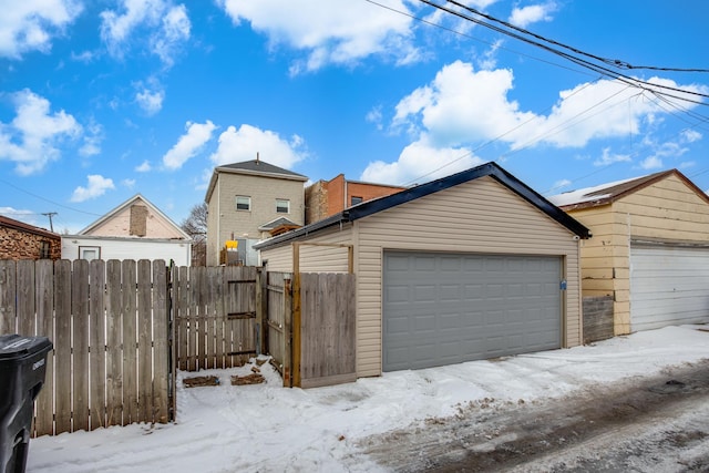 snow covered garage with a garage and fence