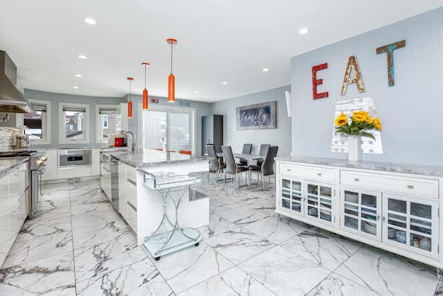 kitchen featuring recessed lighting, a sink, appliances with stainless steel finishes, wall chimney range hood, and marble finish floor