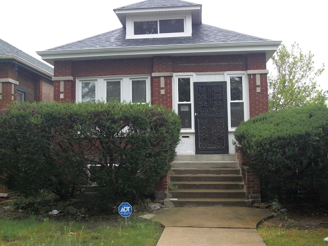 view of front of home featuring brick siding, entry steps, and roof with shingles