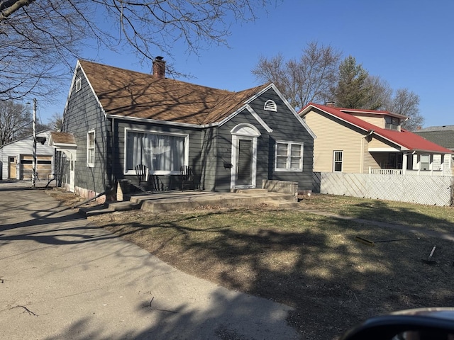 bungalow with a garage, a chimney, an outdoor structure, and fence