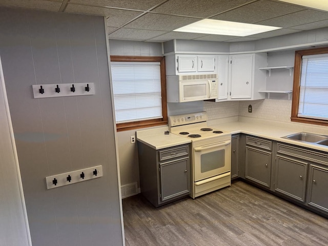 kitchen featuring white appliances, dark wood-style floors, gray cabinets, a sink, and light countertops