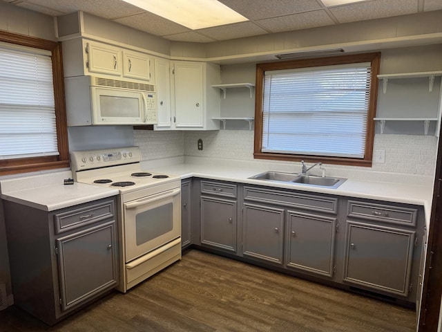 kitchen featuring gray cabinetry, open shelves, dark wood finished floors, white appliances, and a sink